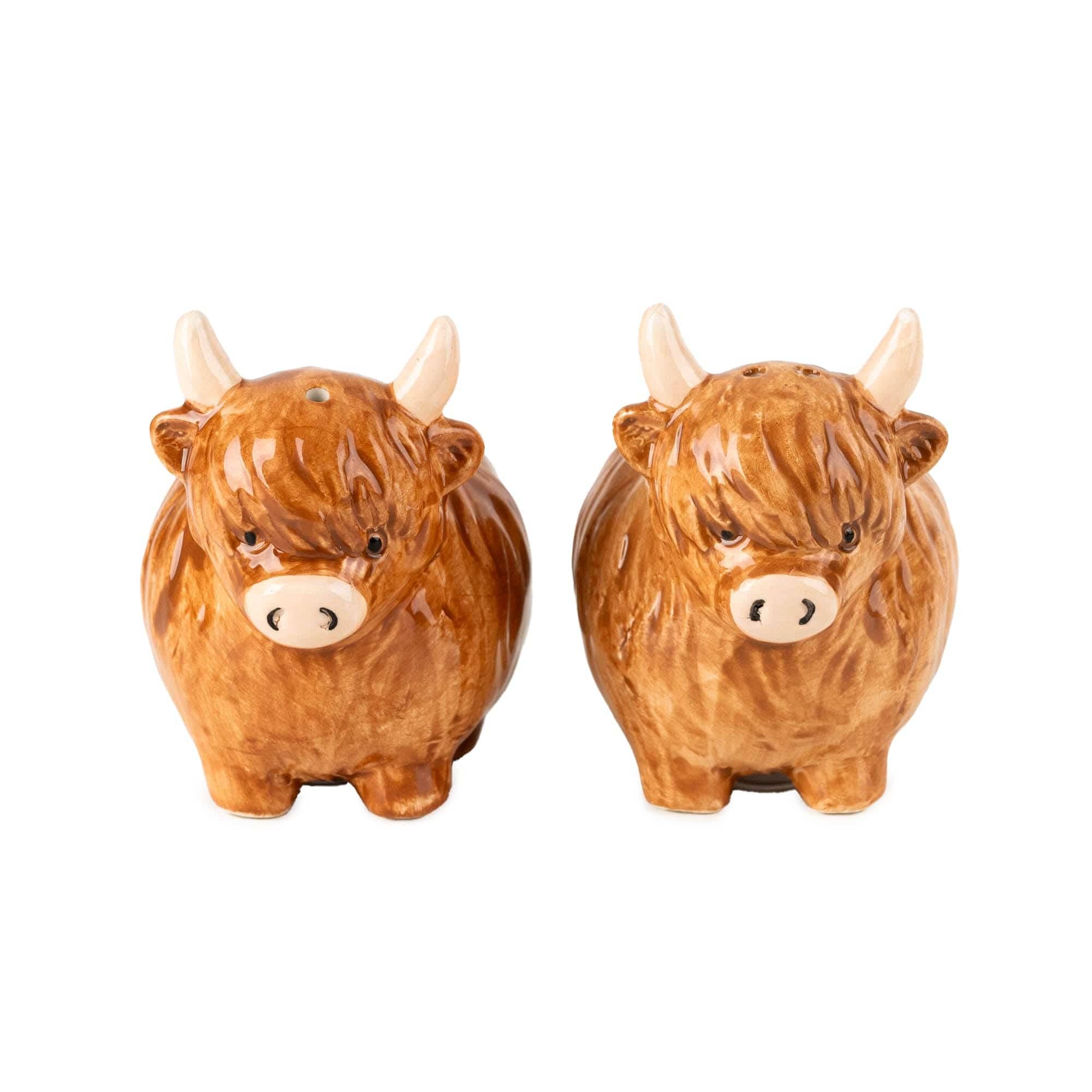 A pair of ceramic salt and pepper shakers shaped like Highland cows, featuring glossy brown bodies, cream-colored horns and snouts, and small black eyes, set against a plain white background.