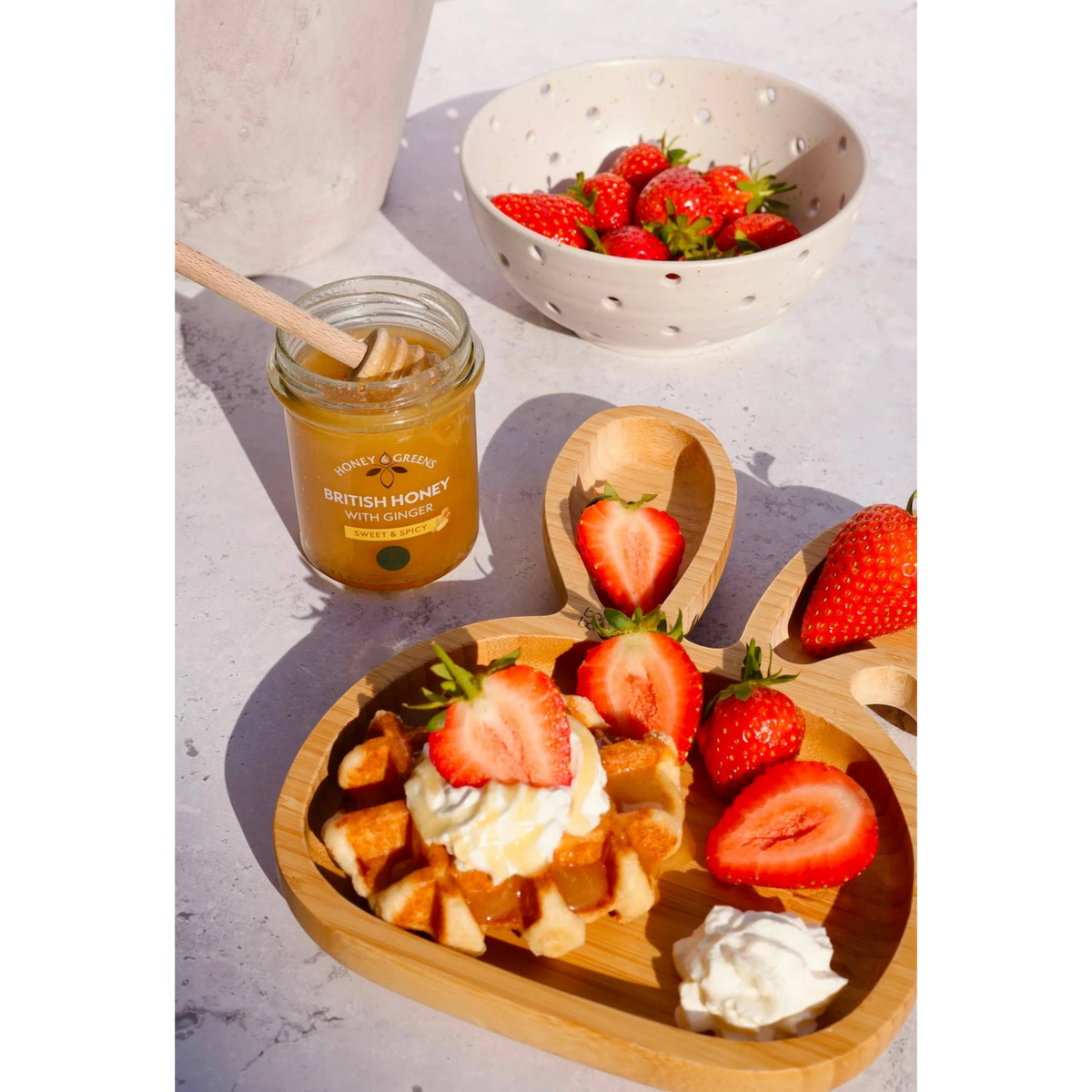 Miele Autentici al gusto di zenzero con cialda, panna e fragole fresche su un vassoio di legno a forma di coniglio
