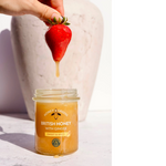 Miele Autentici al gusto di zenzero in vasetto di vetro con una fragola fresca immersa nel miele dorato